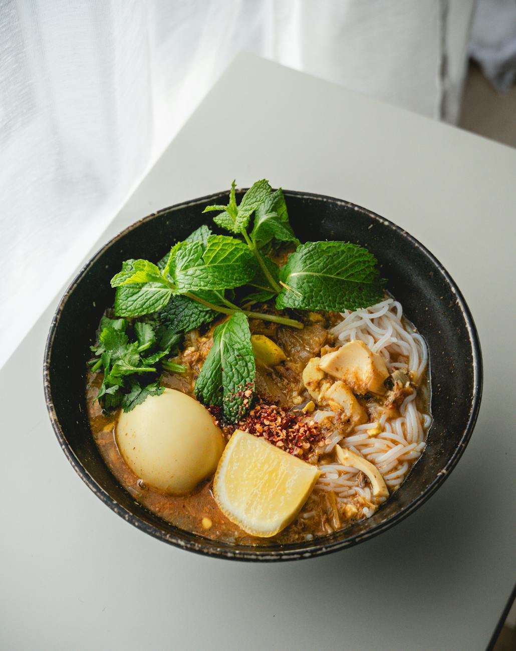 traditional burmese noodle soup with egg and mint