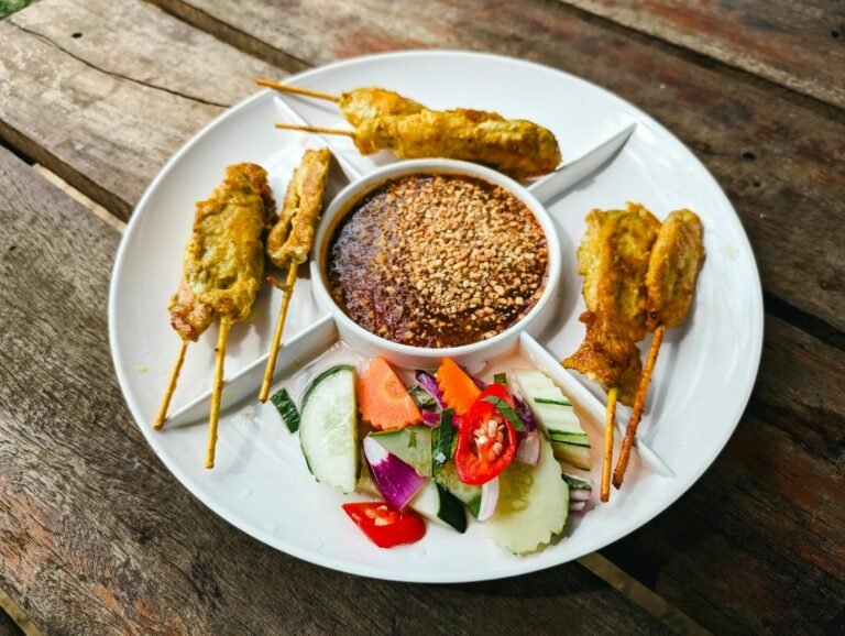 close up of satay with sauce and salad on a plate