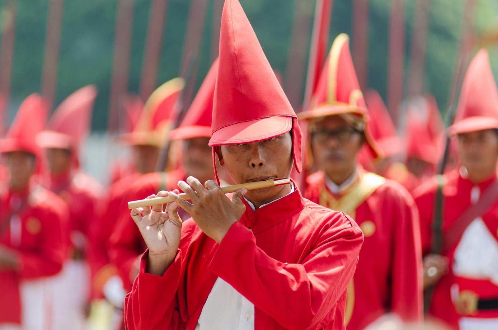 man wearing red hat and uniform playing flute